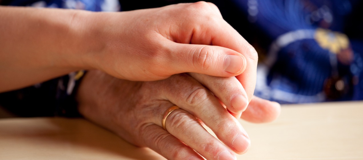 En ung person håller en äldre persons hand i sin.